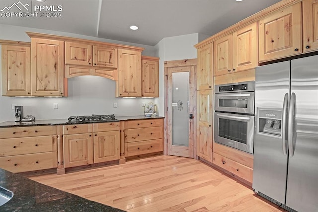 kitchen featuring dark stone countertops, stainless steel appliances, light brown cabinetry, light wood-type flooring, and recessed lighting