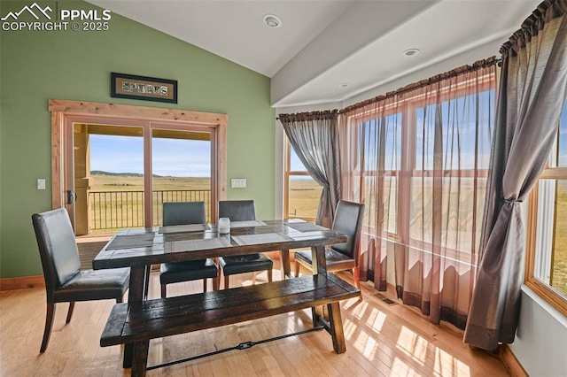 dining area with vaulted ceiling, light wood finished floors, and baseboards