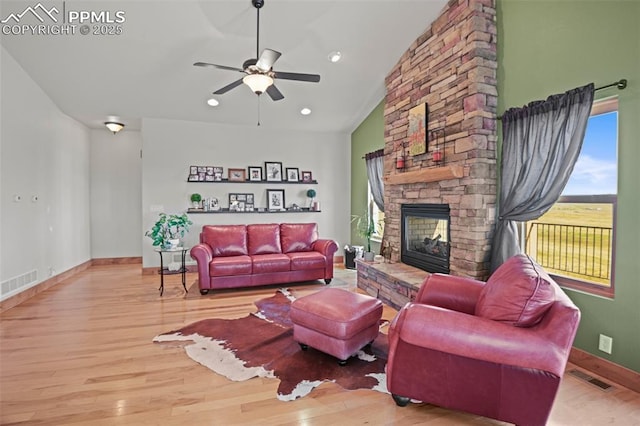 living room with lofted ceiling, visible vents, a fireplace, and wood finished floors