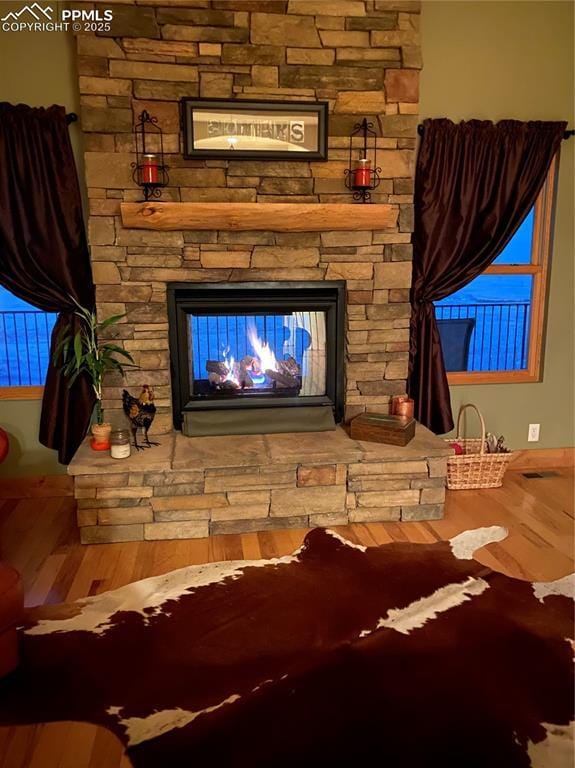 room details with visible vents, wood finished floors, and a stone fireplace