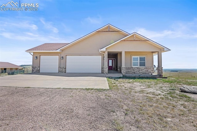 view of front of home with driveway, stone siding, an attached garage, and stucco siding