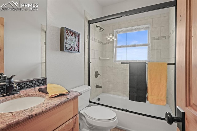 bathroom featuring toilet, bath / shower combo with glass door, backsplash, and vanity