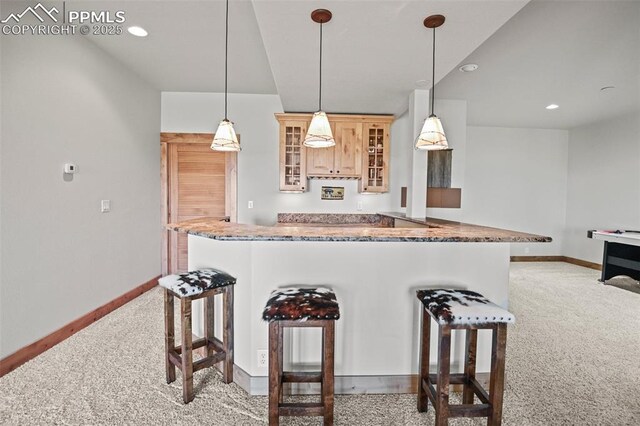 kitchen with baseboards, a kitchen bar, and light colored carpet