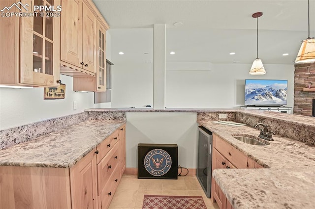 kitchen with wine cooler, glass insert cabinets, light stone counters, light brown cabinetry, and a sink