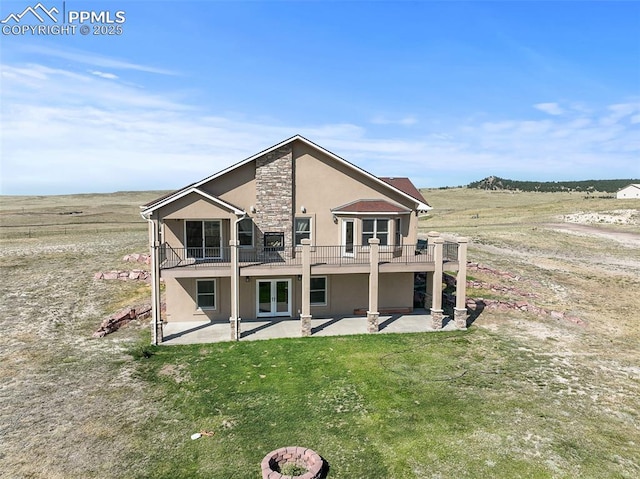 rear view of house featuring a yard, stone siding, a patio, and stucco siding