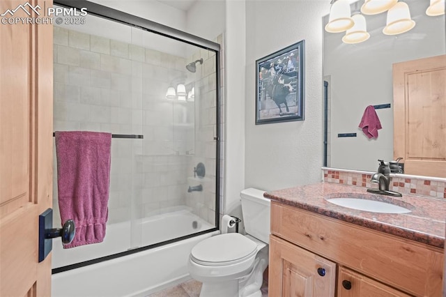 bathroom with toilet, combined bath / shower with glass door, and vanity