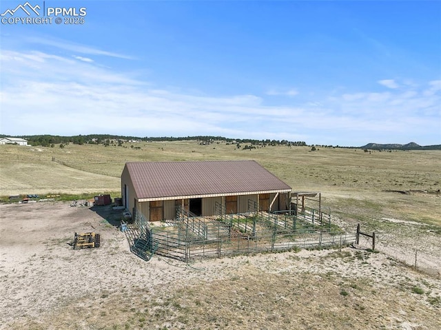 view of front facade featuring metal roof, a rural view, an outdoor structure, and an exterior structure