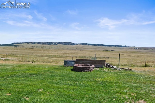 view of yard with a rural view, fence, and a fire pit