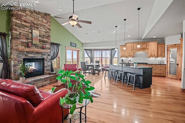 living room with a ceiling fan, a stone fireplace, light wood-style floors, high vaulted ceiling, and recessed lighting