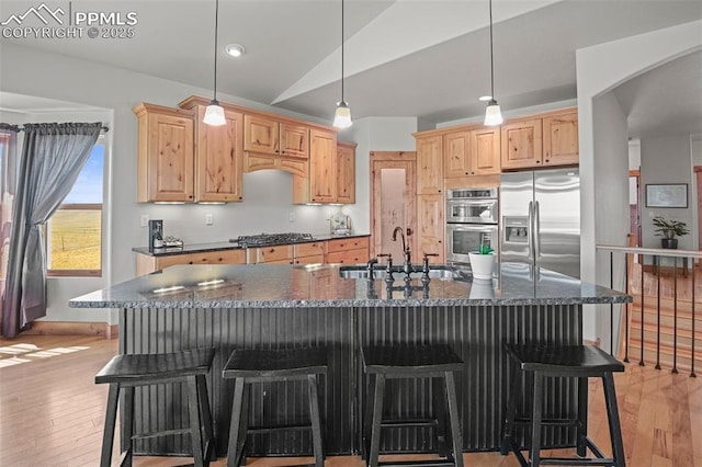 kitchen featuring stainless steel appliances, a sink, light wood-style flooring, and light brown cabinetry