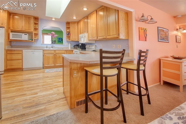 kitchen featuring open shelves, light countertops, light brown cabinets, white appliances, and a peninsula