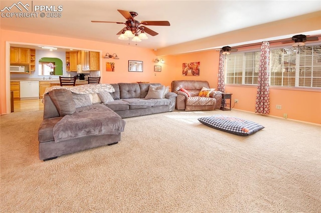 living area with light carpet, ceiling fan, and baseboards