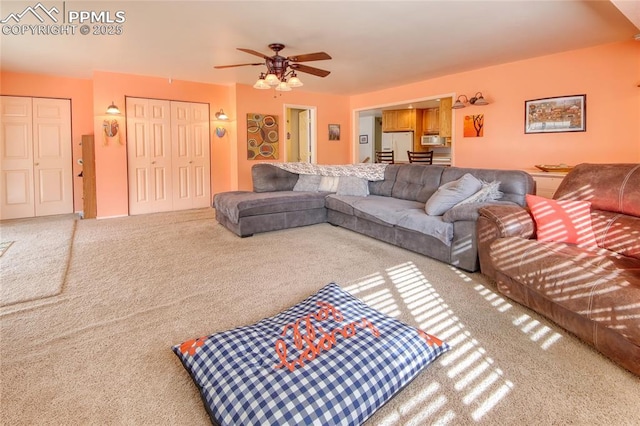 carpeted living area with ceiling fan