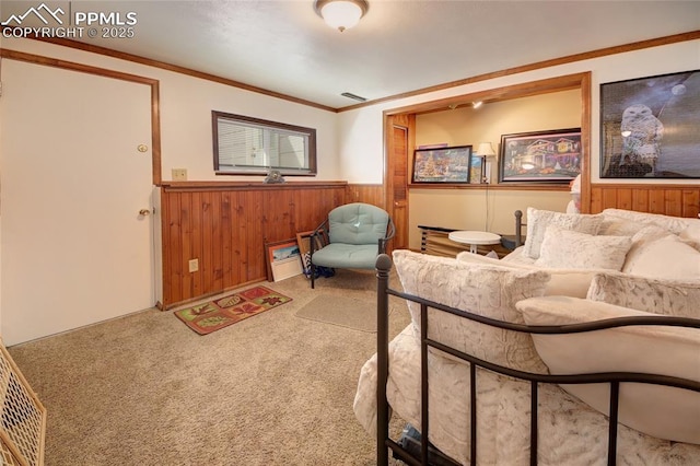 sitting room with a wainscoted wall, ornamental molding, carpet, and wooden walls