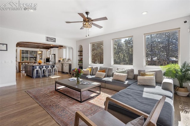 living area with arched walkways, dark wood-style floors, and a wealth of natural light