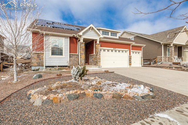 view of front of home with a garage, solar panels, stone siding, and driveway