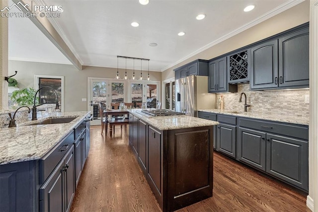 kitchen featuring appliances with stainless steel finishes, dark wood-style flooring, a sink, and a center island