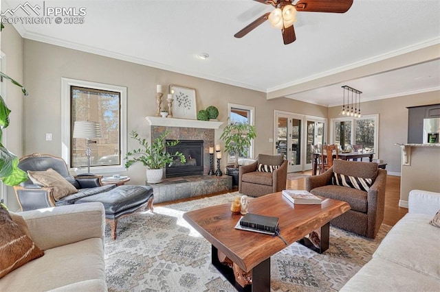 living area with ornamental molding, a fireplace, baseboards, and wood finished floors