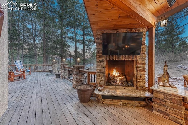 wooden terrace with an outdoor stone fireplace