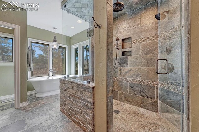 bathroom featuring a wealth of natural light, a freestanding bath, a tile shower, and baseboards