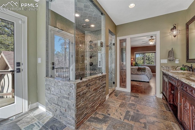 full bath with stone tile floors, a stall shower, vanity, ensuite bath, and baseboards