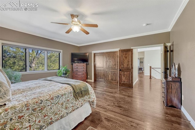 bedroom with a closet, dark wood-type flooring, ornamental molding, a ceiling fan, and baseboards