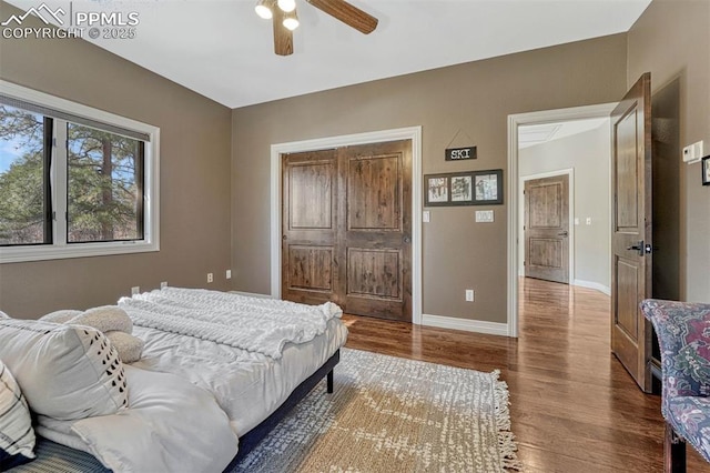 bedroom featuring a ceiling fan, baseboards, and wood finished floors