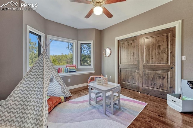 recreation room with ceiling fan, baseboards, and wood finished floors