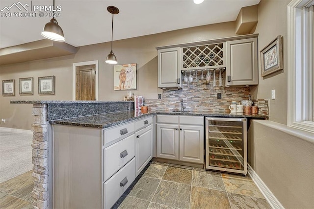 interior space with tasteful backsplash, baseboards, wine cooler, decorative light fixtures, and wet bar