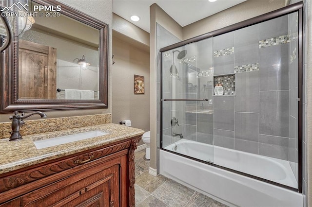 full bathroom featuring toilet, a textured wall, enclosed tub / shower combo, and vanity