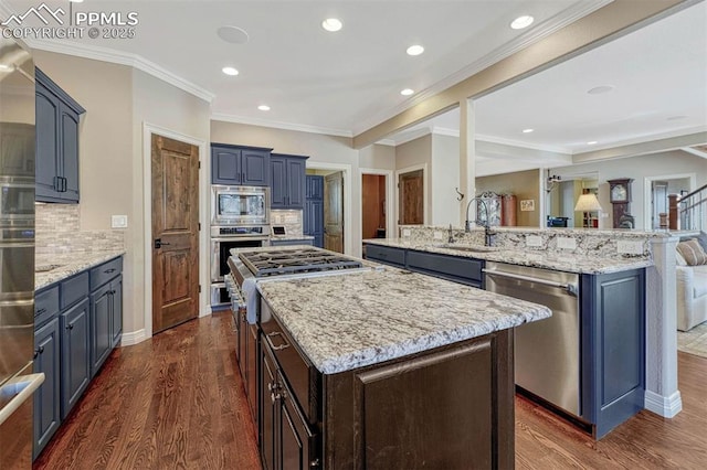 kitchen featuring appliances with stainless steel finishes, dark wood-type flooring, a sink, and a kitchen island