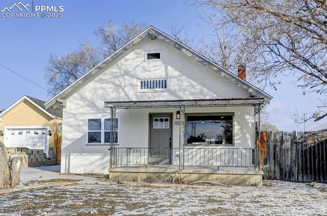 view of front of home featuring a porch, a chimney, fence, and stucco siding