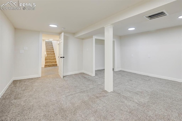 finished below grade area featuring visible vents, light carpet, baseboards, and stairs