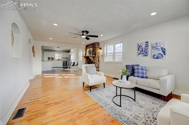 living room with visible vents, arched walkways, baseboards, light wood-style flooring, and recessed lighting