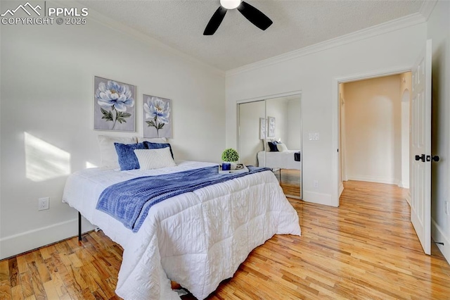 bedroom with a textured ceiling, wood finished floors, baseboards, ornamental molding, and a closet