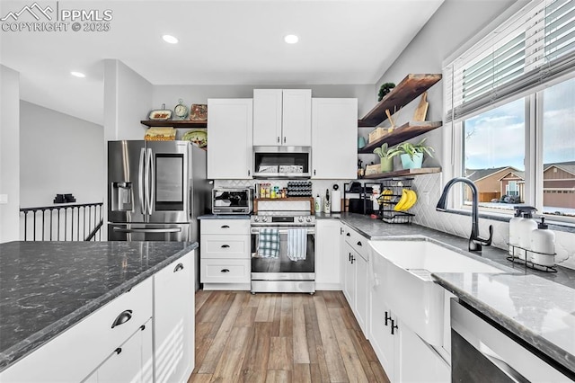 kitchen with appliances with stainless steel finishes, dark stone counters, white cabinets, and open shelves