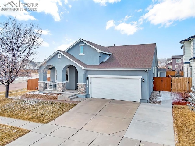 view of front of home featuring stucco siding, covered porch, an attached garage, fence, and driveway