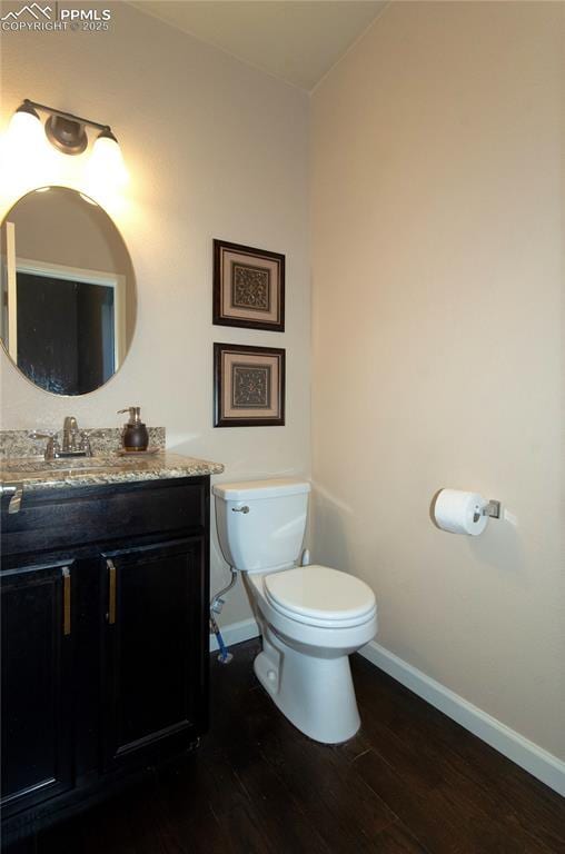 bathroom featuring baseboards, vanity, toilet, and wood finished floors