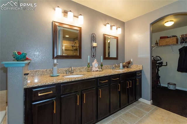 bathroom featuring double vanity, tile patterned flooring, a sink, and a walk in closet