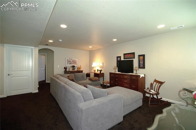 living room featuring visible vents, arched walkways, baseboards, dark colored carpet, and recessed lighting