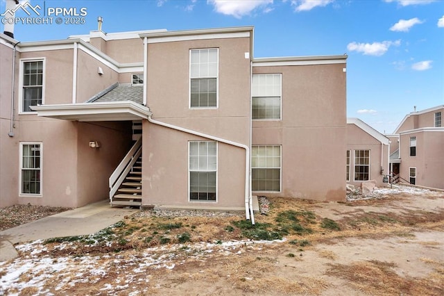 rear view of property with stairway and stucco siding