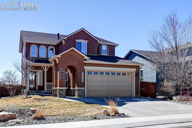 traditional home featuring driveway, stone siding, fence, and stucco siding