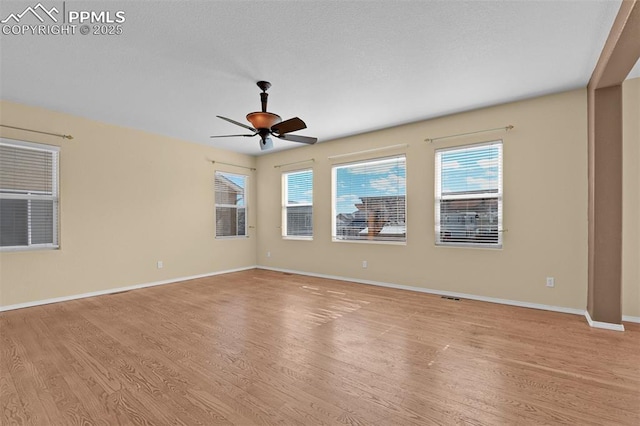 spare room with baseboards, a ceiling fan, and light wood-style floors