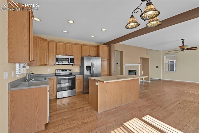 kitchen with light wood-style flooring, a kitchen island, stainless steel appliances, and a sink