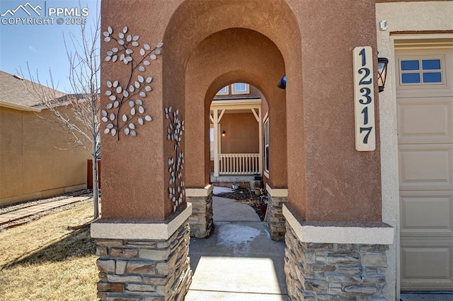 entrance to property with a garage and stucco siding