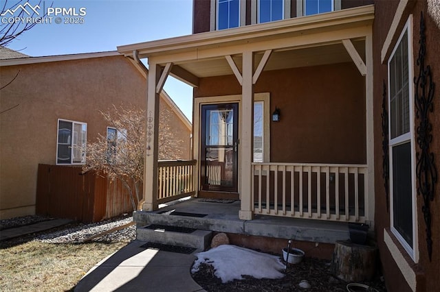 doorway to property featuring covered porch and stucco siding