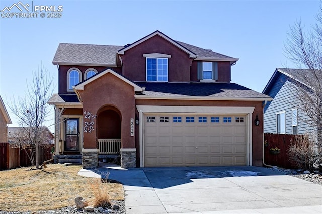 traditional home featuring a garage, driveway, fence, and stucco siding