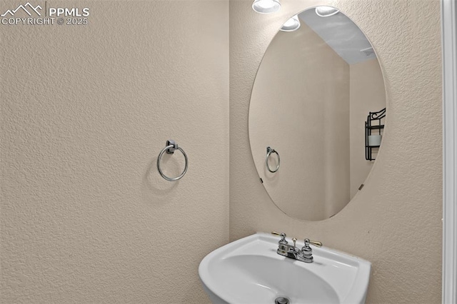 bathroom featuring a textured wall and a sink