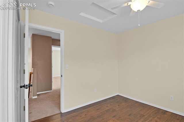 spare room with dark wood-style flooring, attic access, and baseboards