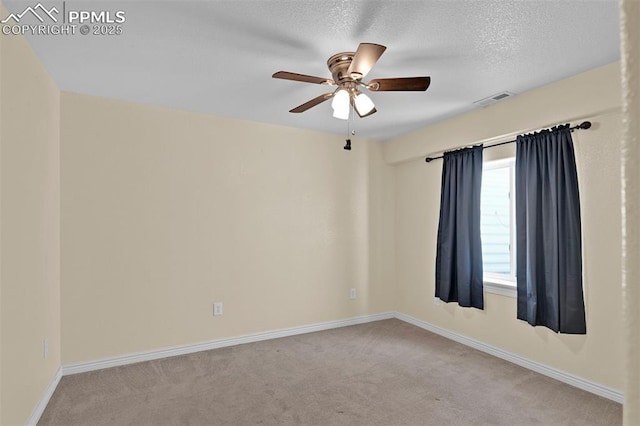 empty room with baseboards, visible vents, a ceiling fan, light colored carpet, and a textured ceiling